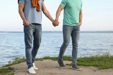 Photo of Gay couple walking near river on sunny day, closeup