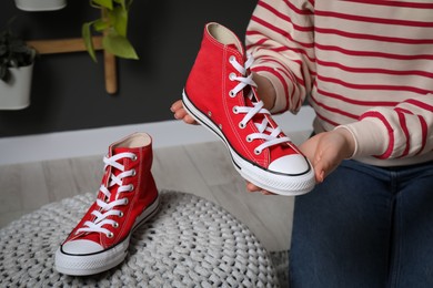 Photo of Woman with new stylish red sneakers indoors, closeup
