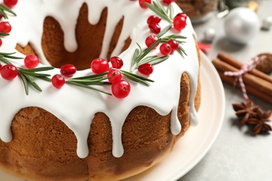 Photo of Traditional Christmas cake decorated with glaze, pomegranate seeds, cranberries and rosemary on light table, closeup