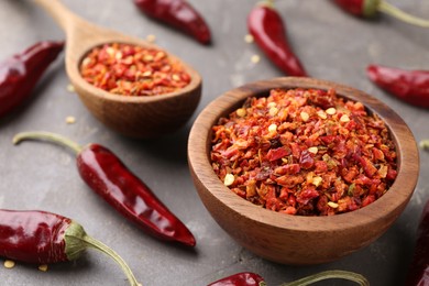 Photo of Chili pepper flakes and pods on grey table, closeup