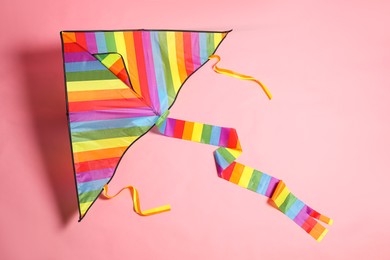 Photo of Bright rainbow kite on pink background, top view