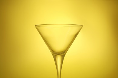 Photo of Elegant empty martini glass on yellow background, closeup