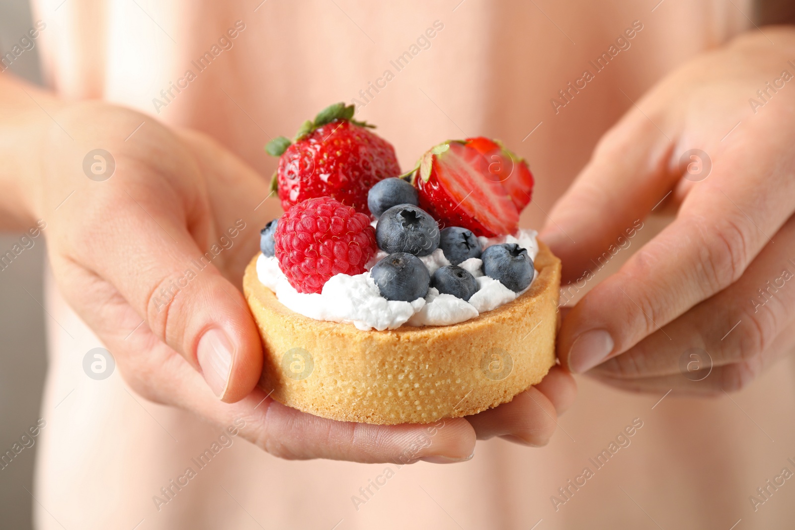 Photo of Woman holding tart with different berries, closeup. Delicious pastries