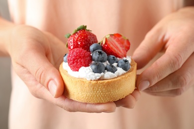 Photo of Woman holding tart with different berries, closeup. Delicious pastries