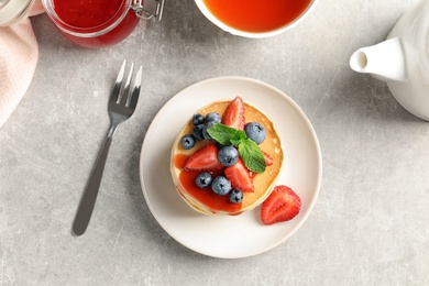 Plate with pancakes and berries on grey background, top view