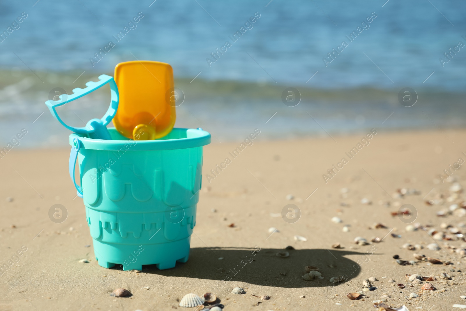 Photo of Different child plastic toys on sandy beach. Space for text