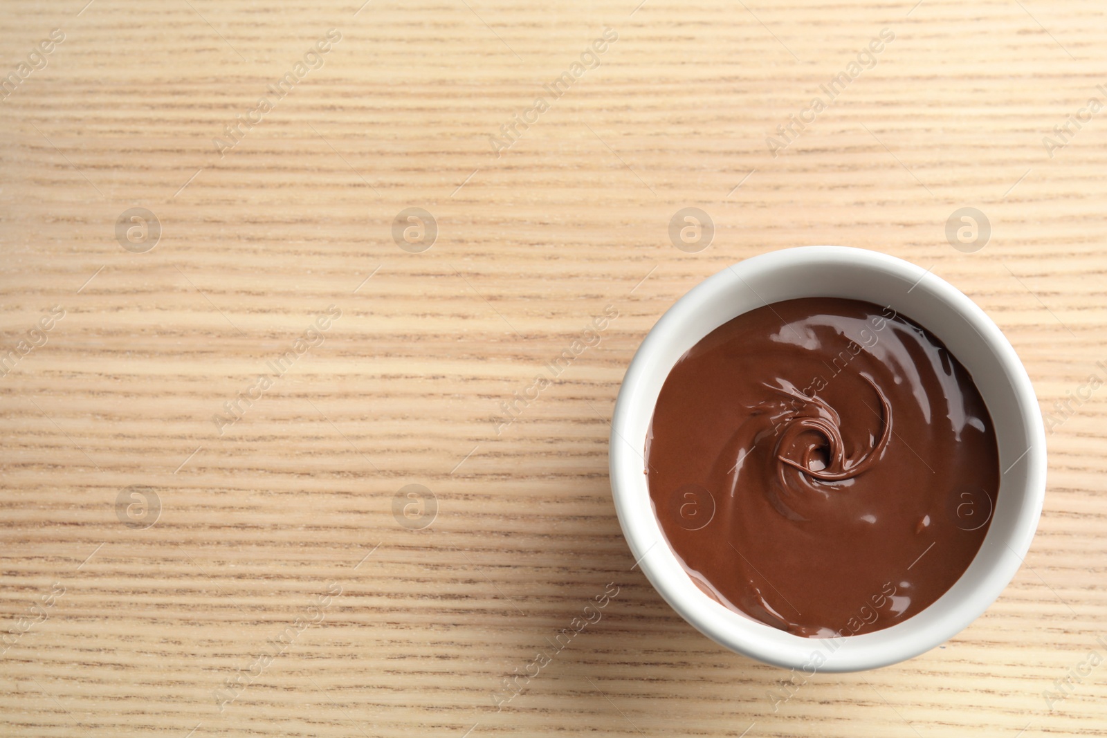 Photo of Bowl with sweet chocolate cream on wooden background, top view. Space for text