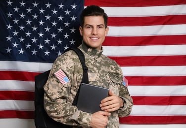 Photo of Cadet with backpack and tablet against American flag. Military education