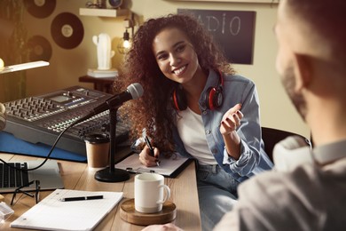 Photo of Young African American woman interviewing man in modern radio studio