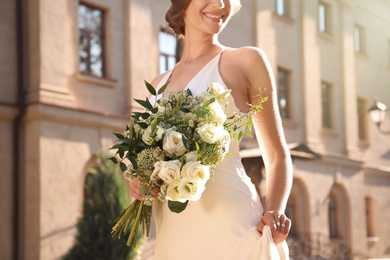 Photo of Bride in beautiful wedding dress with bouquet outdoors, closeup