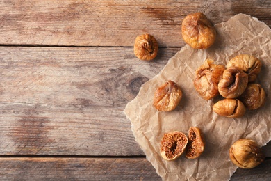 Photo of Parchment with dried figs on wooden background, top view. Space for text