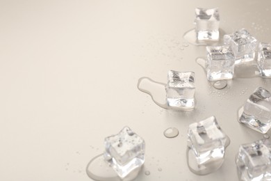 Melting ice cubes and water drops on light grey background, closeup. Space for text
