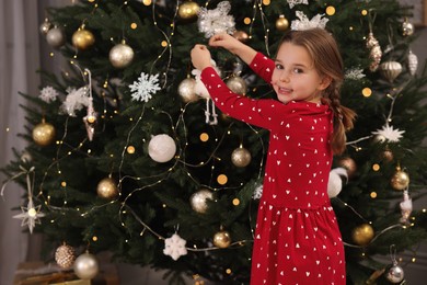 Photo of Cute little child decorating Christmas tree at home