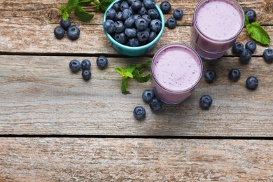 Photo of Freshly made blueberry smoothie on wooden table, flat lay. Space for text
