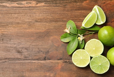 Photo of Composition with fresh ripe limes on wooden background, top view