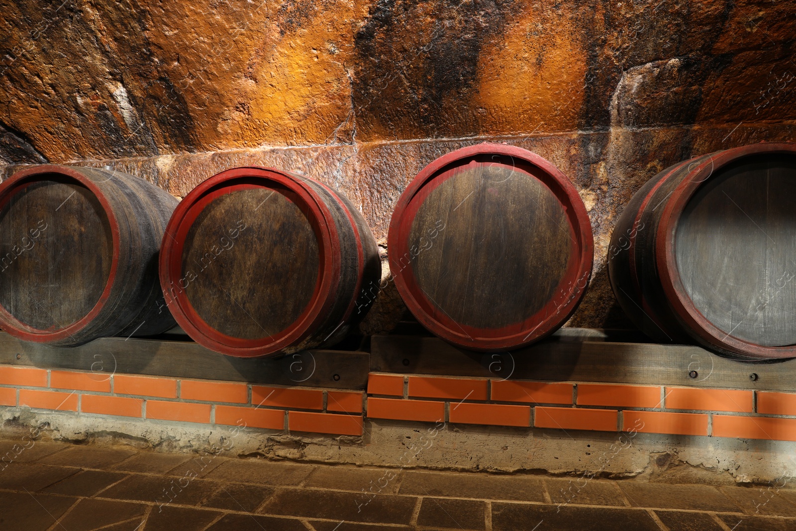 Photo of Many wooden barrels with alcohol drinks in cellar