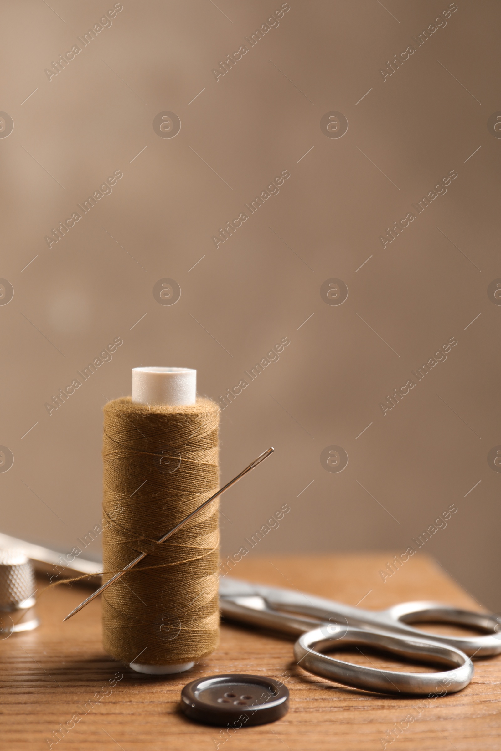 Photo of Scissors and other sewing accessories on wooden table, space for text