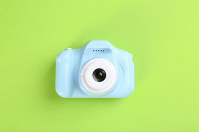 Light blue toy camera on green background, top view