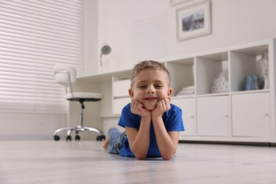 Photo of Cute little boy lying on warm floor at home. Heating system