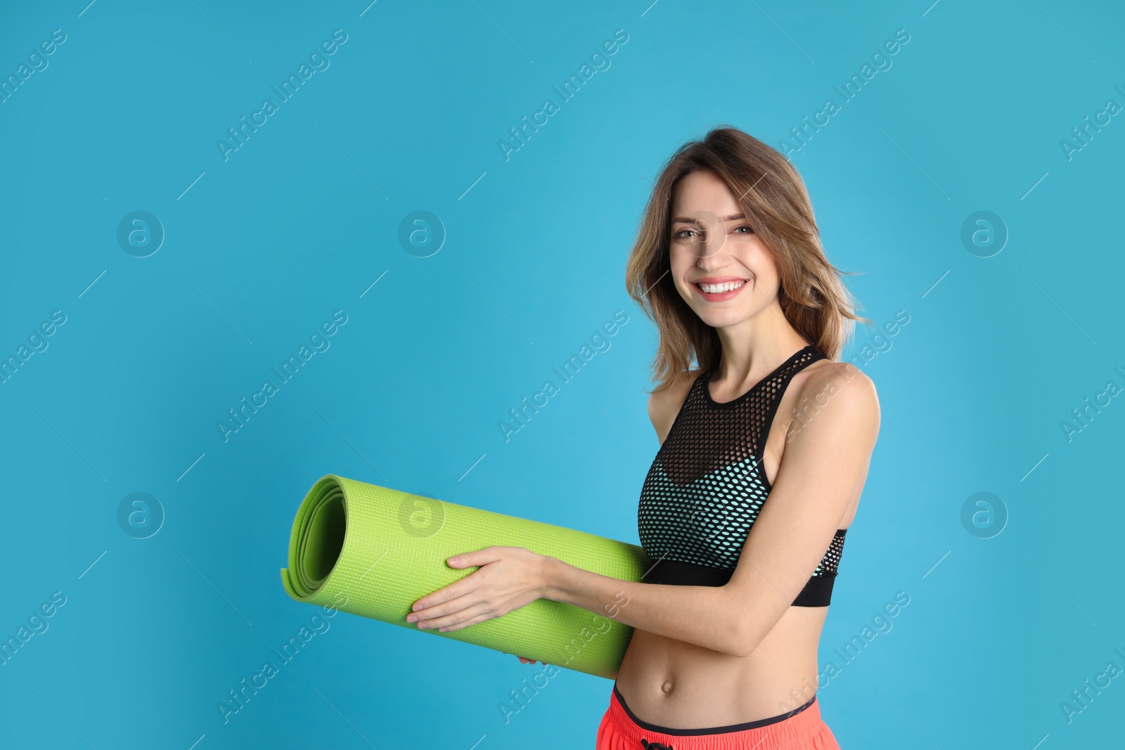 Photo of Beautiful woman with yoga mat on turquoise background. Space for text