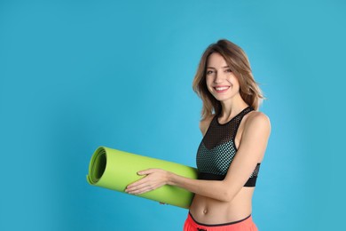 Photo of Beautiful woman with yoga mat on turquoise background. Space for text