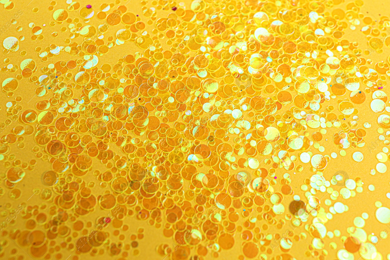 Photo of Shiny bright golden glitter on yellow background