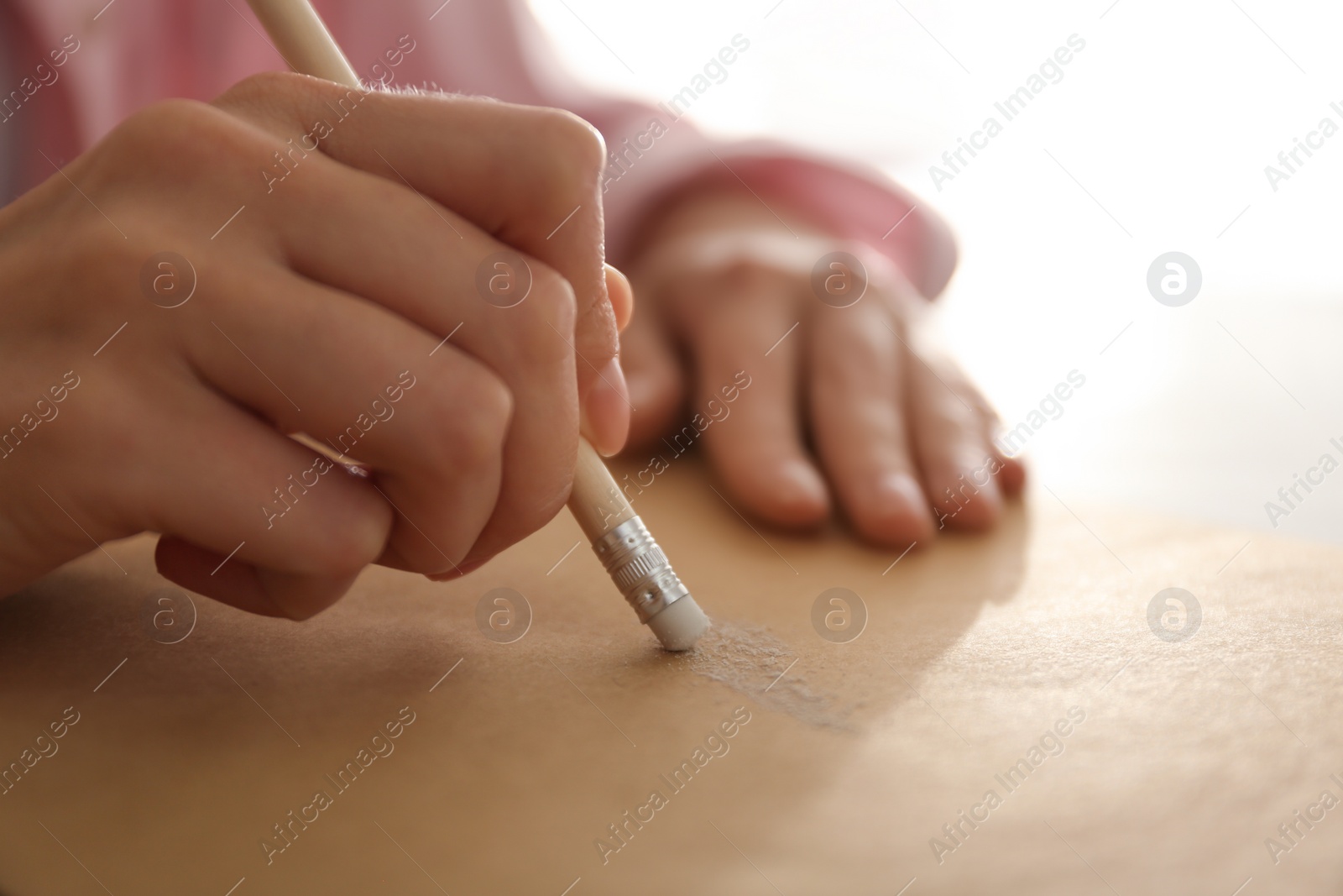 Photo of Woman correcting picture on paper with pencil eraser, closeup