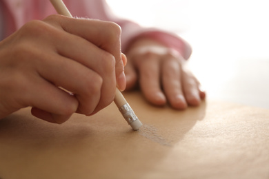 Photo of Woman correcting picture on paper with pencil eraser, closeup