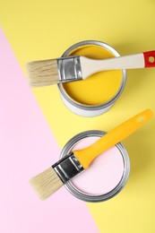 Photo of Cans of different paints with brushes on color background, flat lay