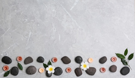 Photo of Flat lay composition with spa stones and lit candles on grey marble background, space for text