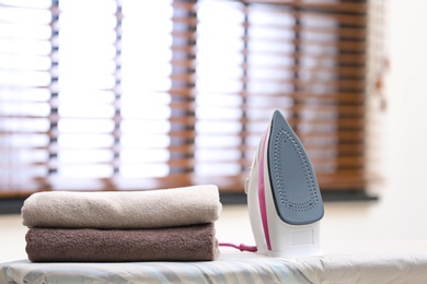 Photo of Modern iron and towels on board in room