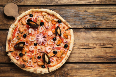 Photo of Delicious seafood pizza on wooden table, top view. Space for text