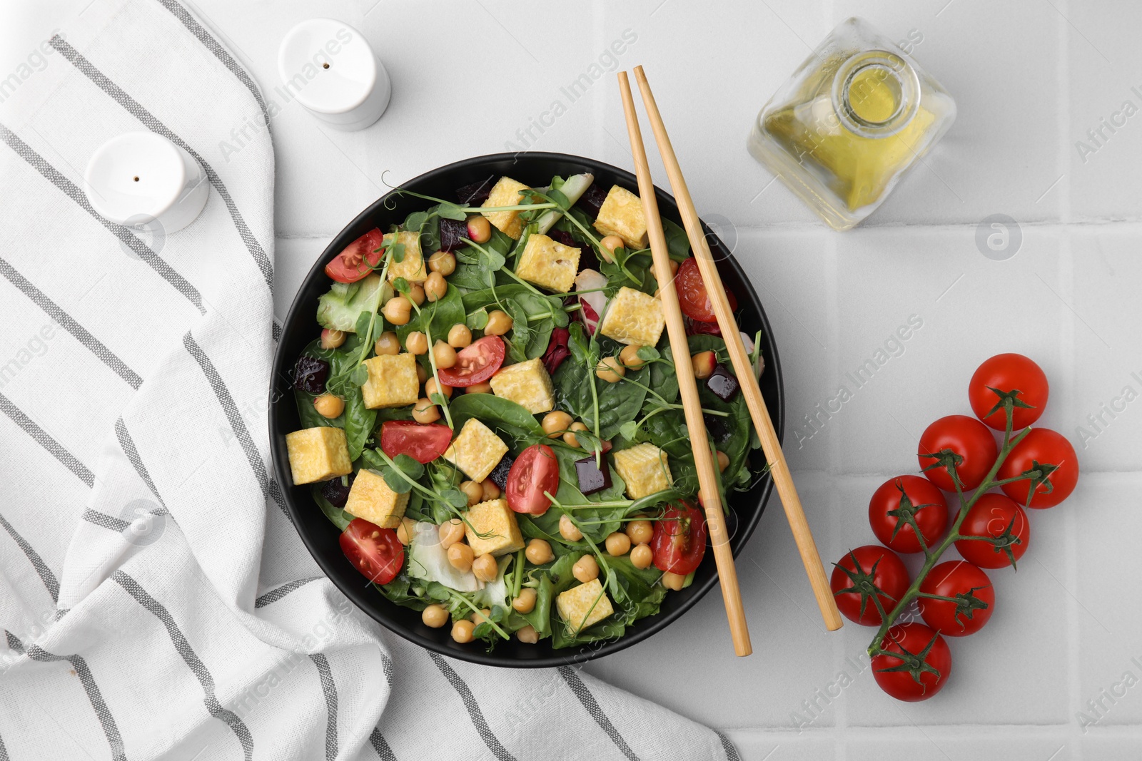 Photo of Tasty salad with tofu, chickpeas and vegetables served on white tiled table, flat lay