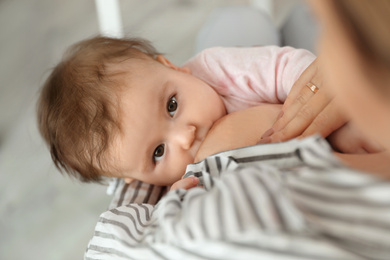 Photo of Young woman breastfeeding her baby at home, closeup