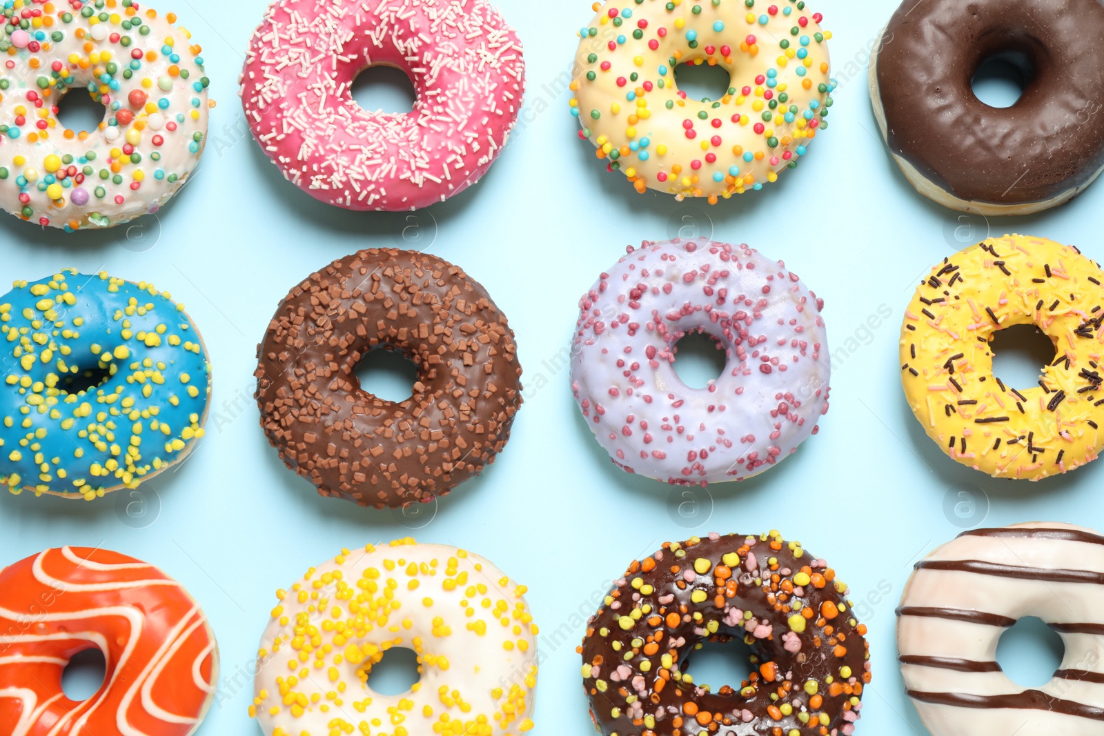 Photo of Delicious glazed donuts on light blue background, flat lay