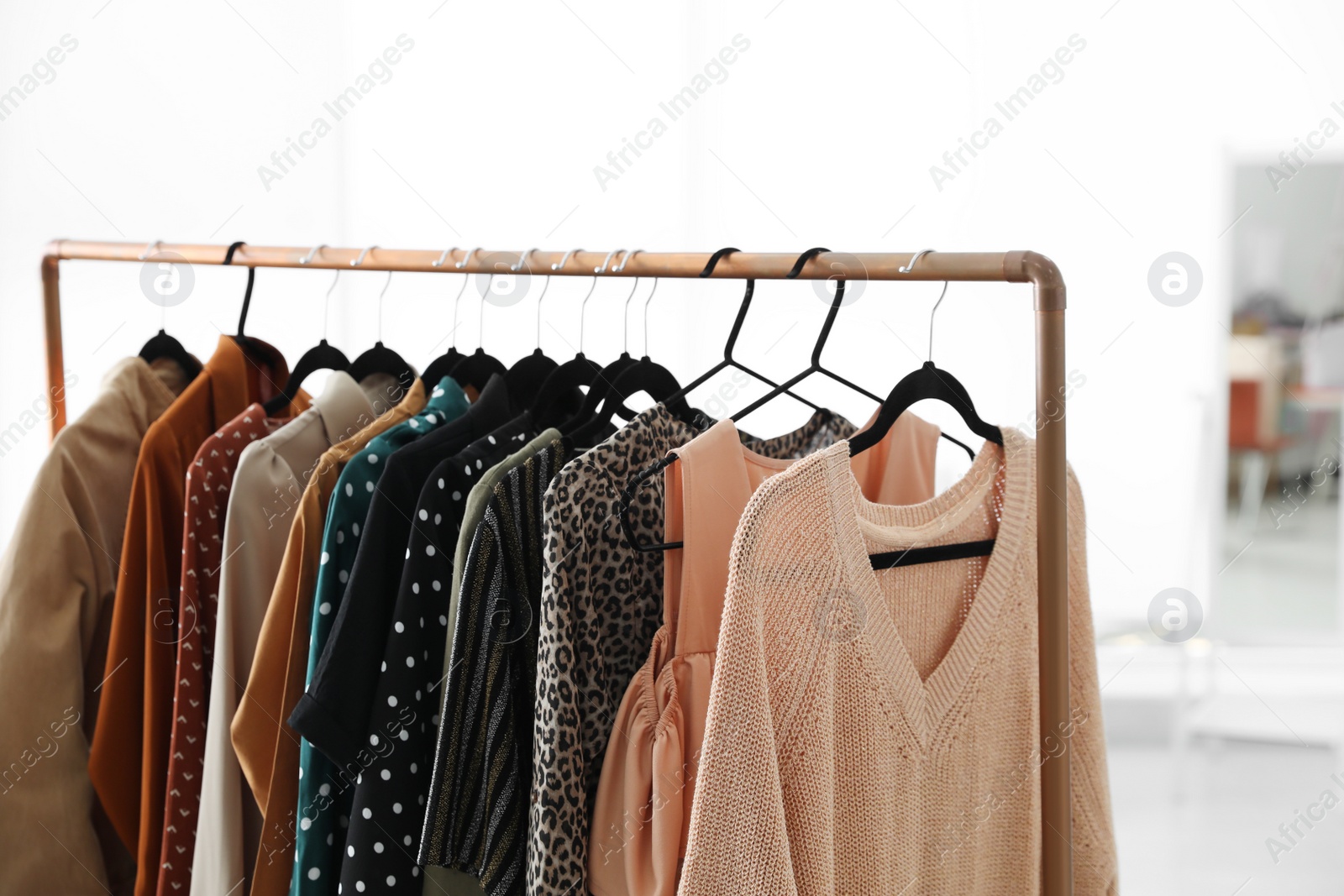 Photo of Different stylish clothes on rack in dressing room, closeup