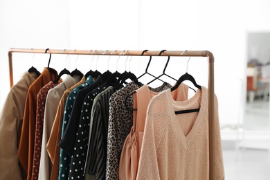 Different stylish clothes on rack in dressing room, closeup