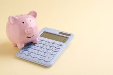 Financial savings. Piggy bank and calculator on beige background, space for text