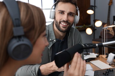 Photo of Man interviewing young woman in modern radio studio, closeup