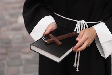 Photo of Young nun with Christian cross and Bible outdoors, closeup