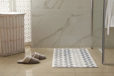 Photo of Soft bath mat and slippers on floor in bathroom