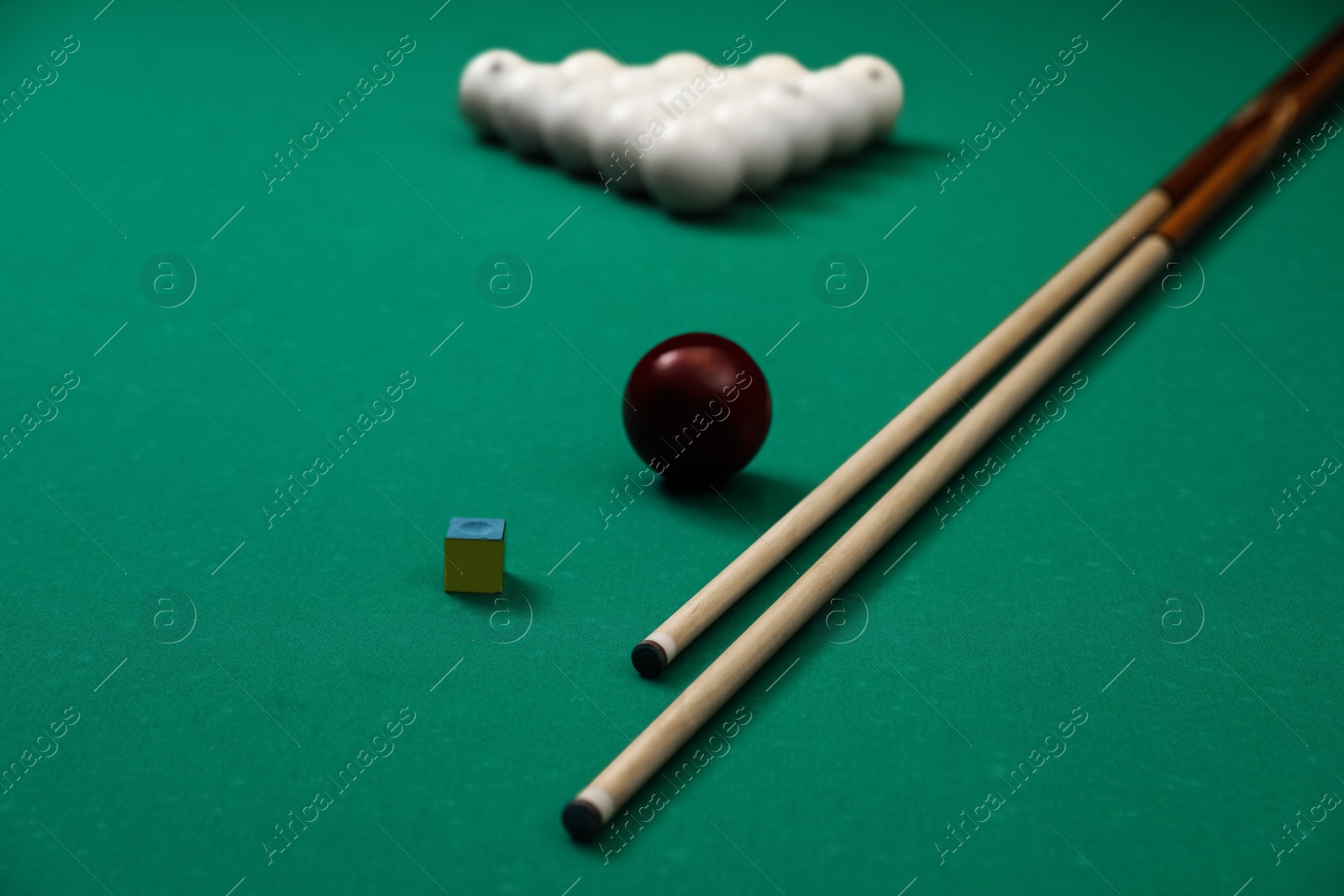 Photo of Billiard balls, chalk and cues on table