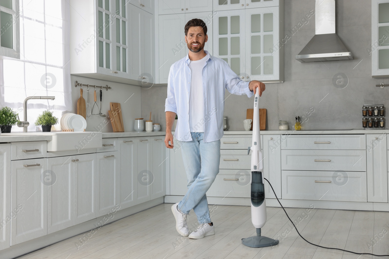 Photo of Happy man with steam mop in kitchen at home