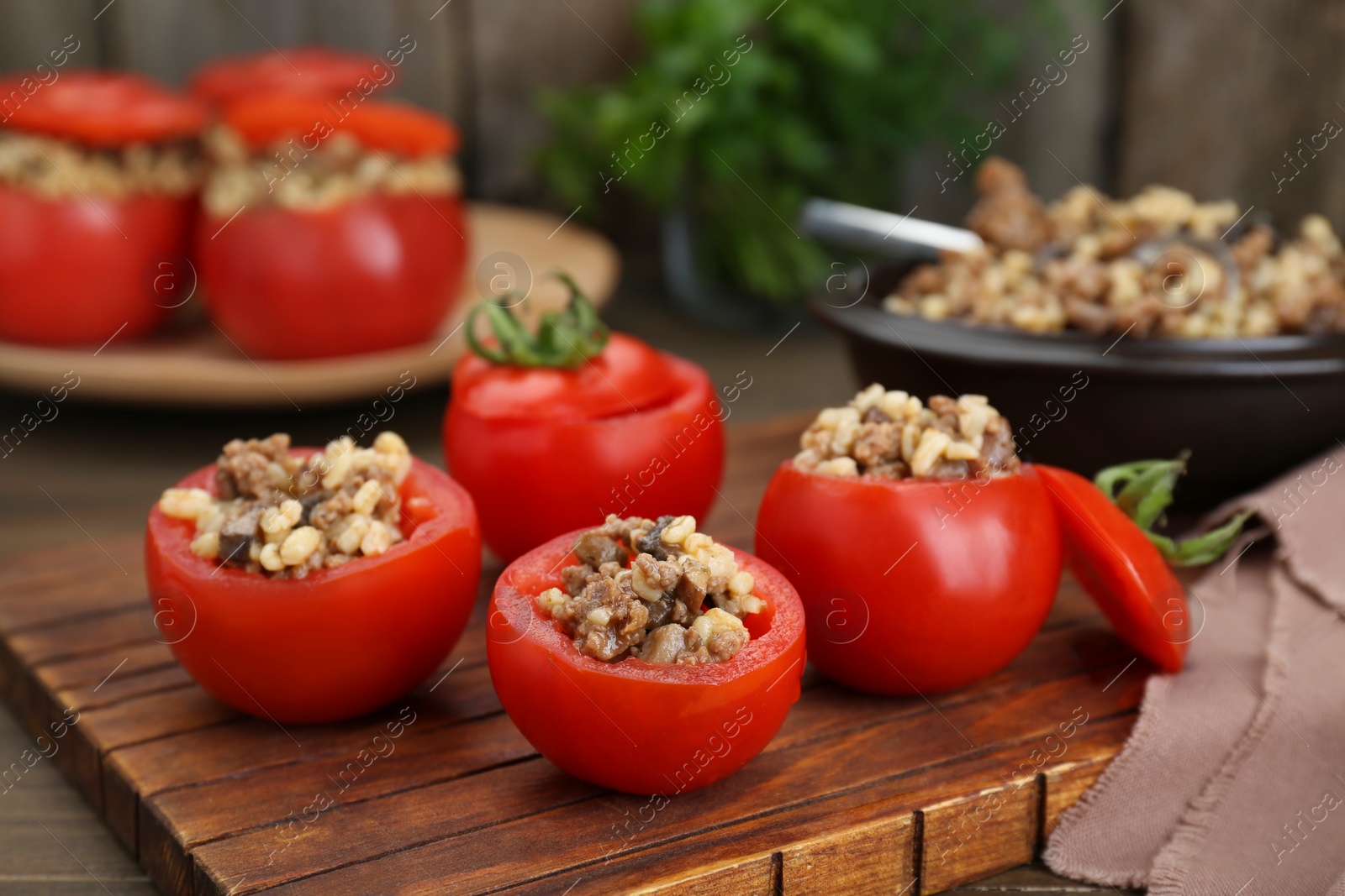 Photo of Delicious stuffed tomatoes with minced beef, bulgur and mushrooms on wooden board