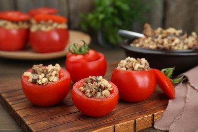 Photo of Delicious stuffed tomatoes with minced beef, bulgur and mushrooms on wooden board