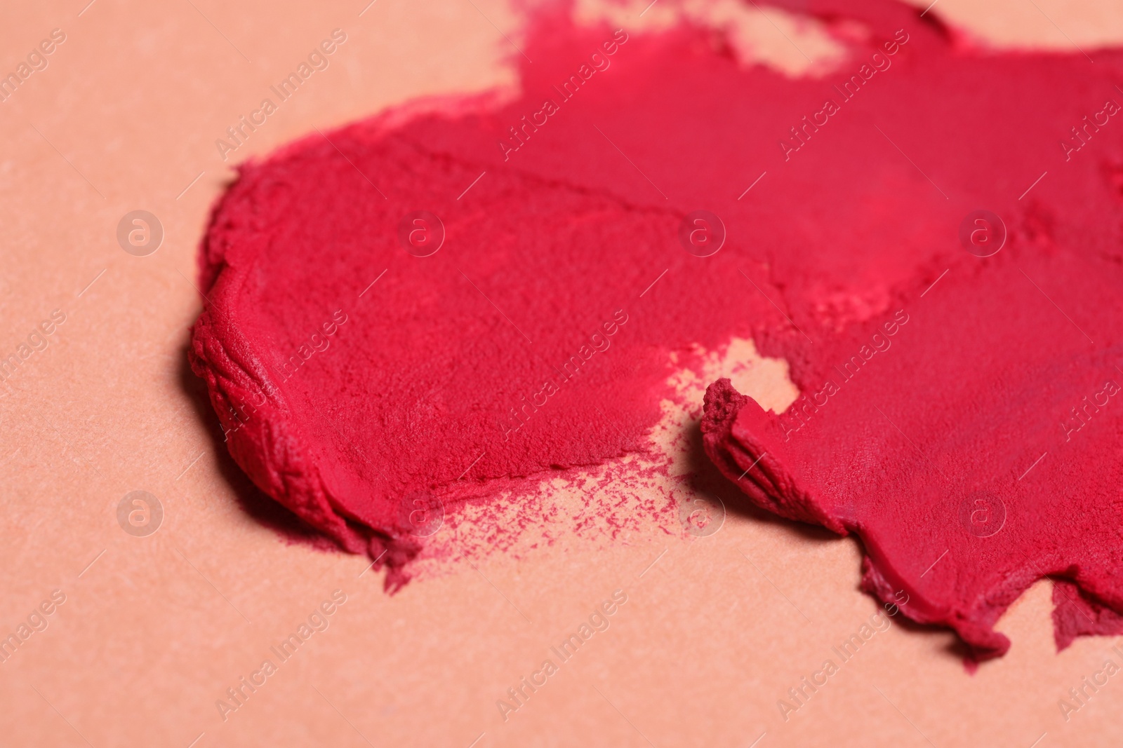 Photo of Smears of beautiful lipstick on beige background, closeup