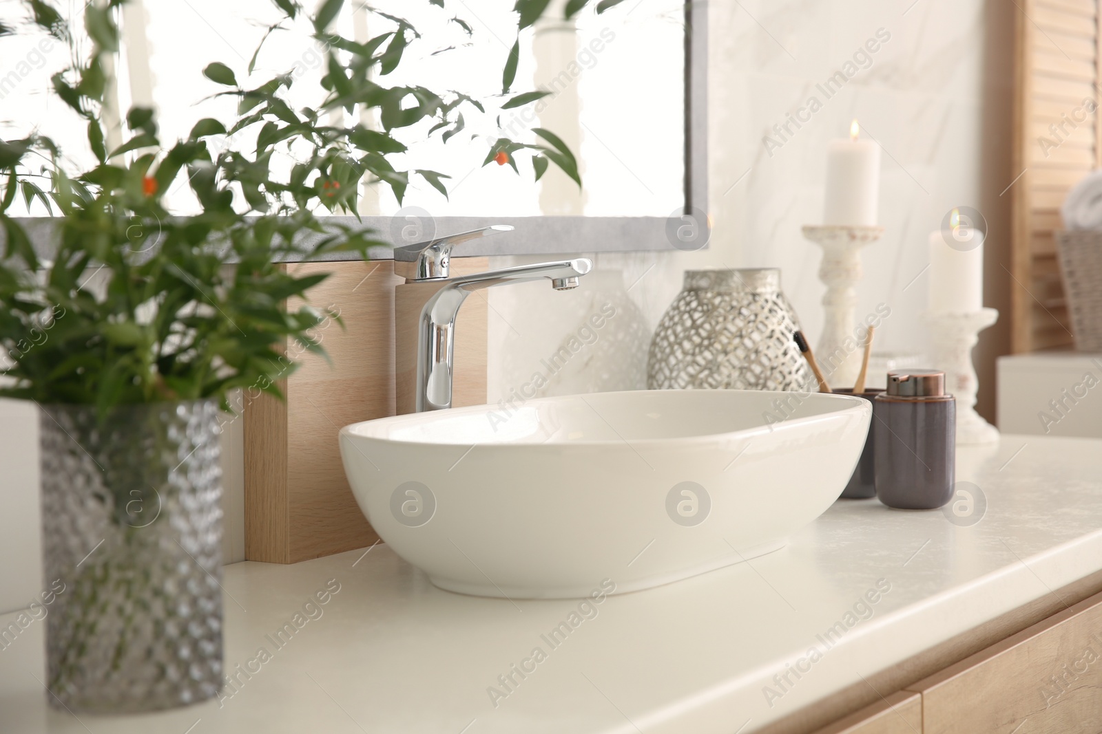 Photo of Vase with beautiful branches and toiletries near vessel sink in bathroom. Interior design