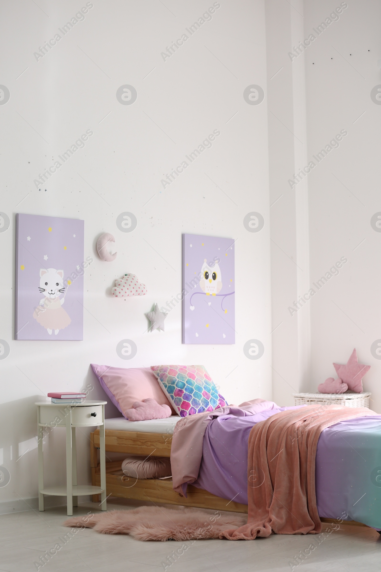 Photo of Bed with colorful linen in stylish children's room. Interior design