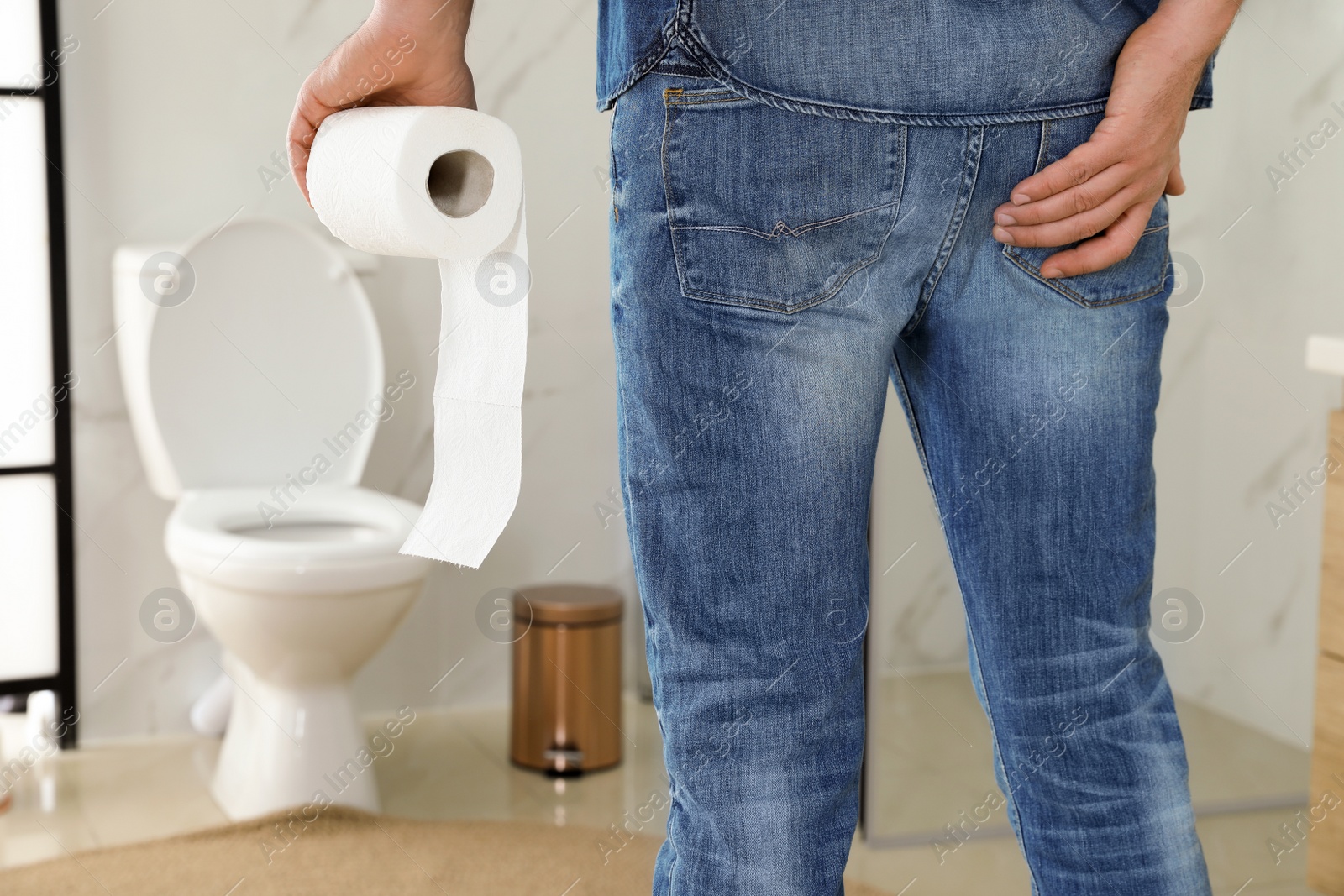 Photo of Man with toilet paper suffering from hemorrhoid in rest room, closeup