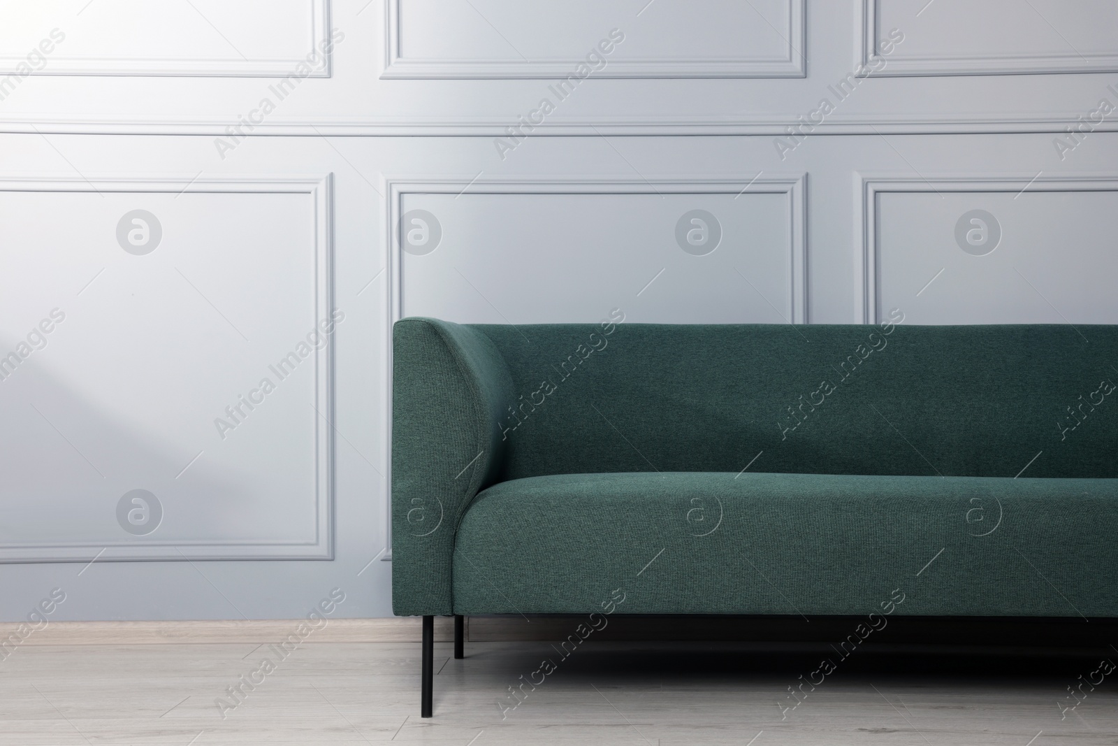 Photo of Comfortable sofa near stylish white wall indoors. Space for text